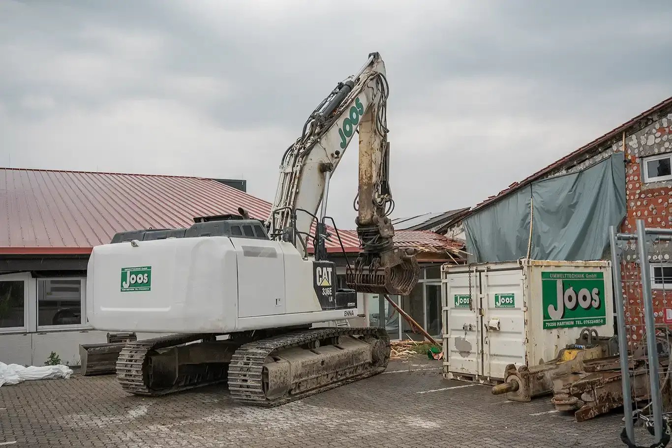 Excavator on a construction site during the development of DEKRA Congresshotel Wart in Germany’s Black Forest. In the background, a partially completed building is visible in the early stages of construction.