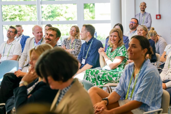 Audience members at MICE Talks Live during the MICE Executive Circle 2026 (MEC 2026) at Lake Starnberg. Participants from procurement, the supplier side, and the wider MICE industry sit engaged in the audience, smiling and enthusiastically following the discussion. MICE Talks Live brings together the perspectives of buyers, suppliers, and the platform at the MICE Portal industry event.