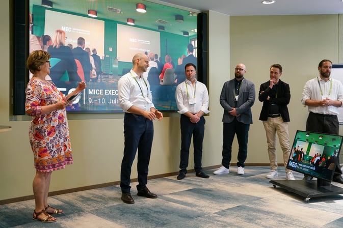 Josephine Gräfin von Brühl, Gründerin von MICE Portal, beim Rückblick auf der Bühne des MICE Executive Circle 2026 (MEC 2026), gemeinsam mit Daniel Ritter, Vinzenz Graf von Brühl, Frederik Fix, Maximilian Graf von Brühl und Philipp Graf von Brühl. Die Führungsriege und nächste Generation von MICE Portal steht zusammen auf der Bühne und präsentiert die Entwicklung des Unternehmens vom Familienunternehmen zur KI-gestützten Plattform für digitalen Veranstaltungseinkauf und strategisches MICE Management.