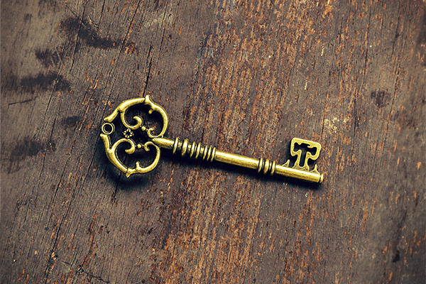 Goldfarbener Schlüssel mit verzierten Details liegt auf einer hölzernen Oberfläche.