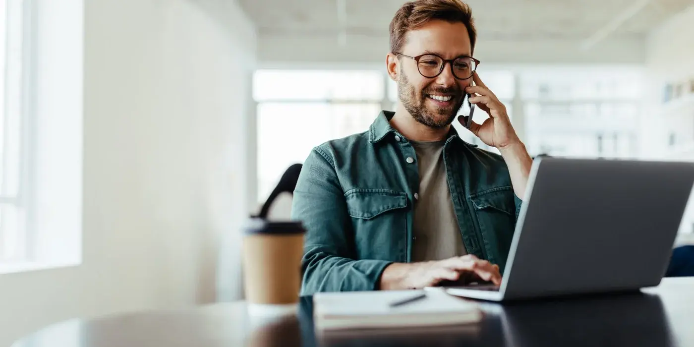 Travel Manager telefoniert am Laptop im Büro und verhandelt Hotelraten für den MICE-Einkauf seines Unternehmens